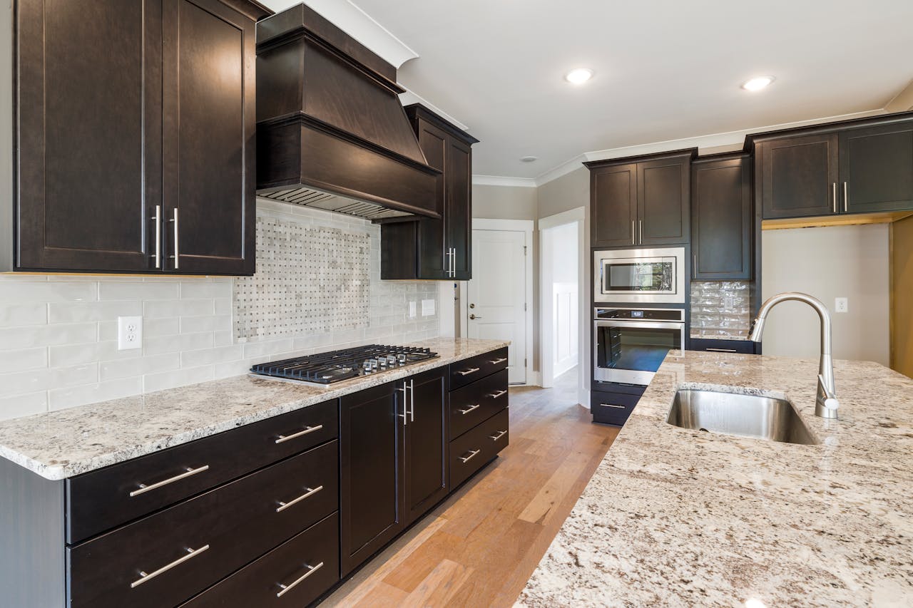 About Contemporary kitchen featuring dark cabinetry, granite countertops, and stainless steel appliances.
